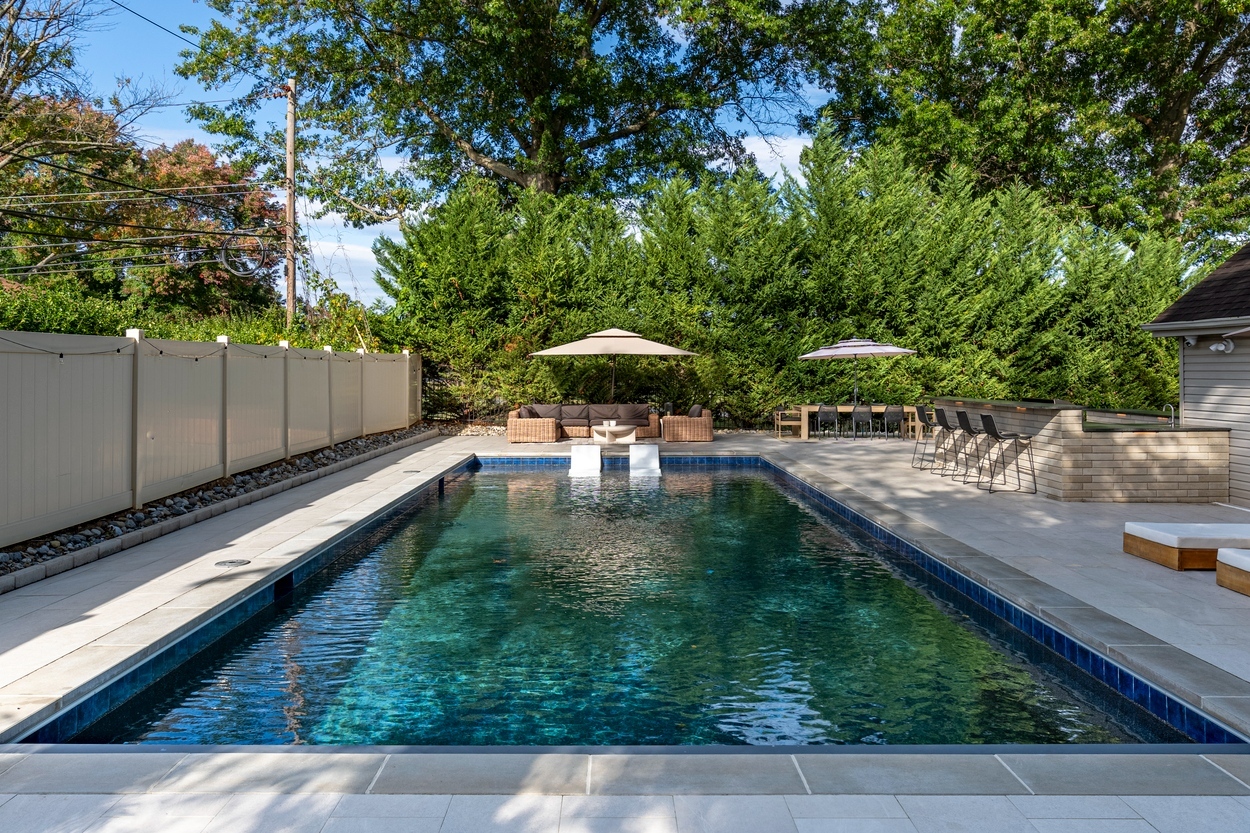 Side view of pool area with lounge chairs and custom hardscaping in Wilmington, DE