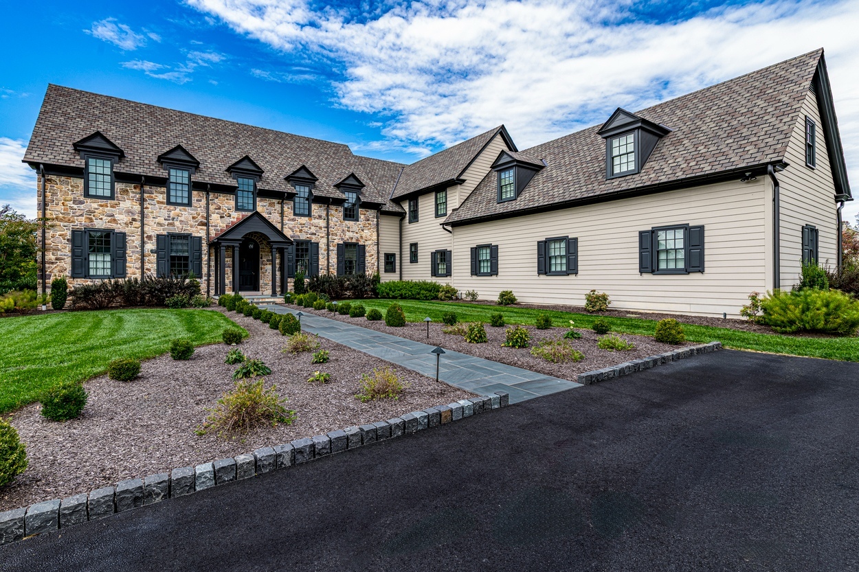 Daytime wide view of front stone home with symmetrical planting and custom hardscaping, landscaping and lighting in Wilmington, DE