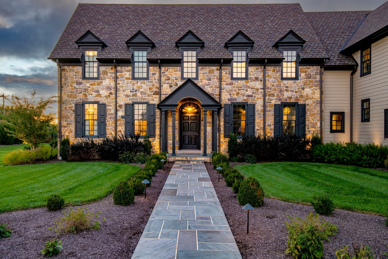 Elegant front walkway leading to a stone facade entrance with custom hardscaping, landscaping and lighting in Wilmington, DE
