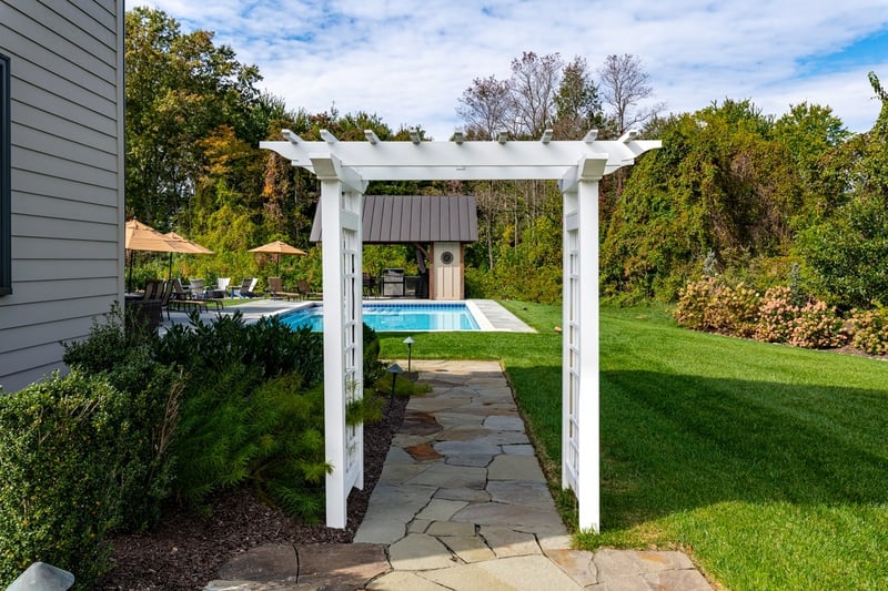 Scenic landscape design around pergola and pool space with custom hardscaping, landscaping and lighting in Wilmington, DE