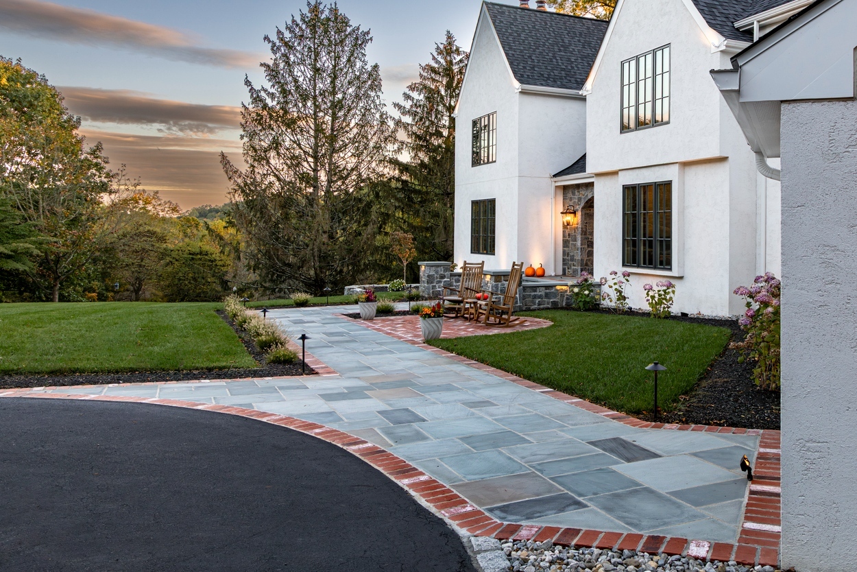 Curved front walkway with brick border and accent lighting showcasing custom hardscaping, landscaping and lighting in Wilmington, DE