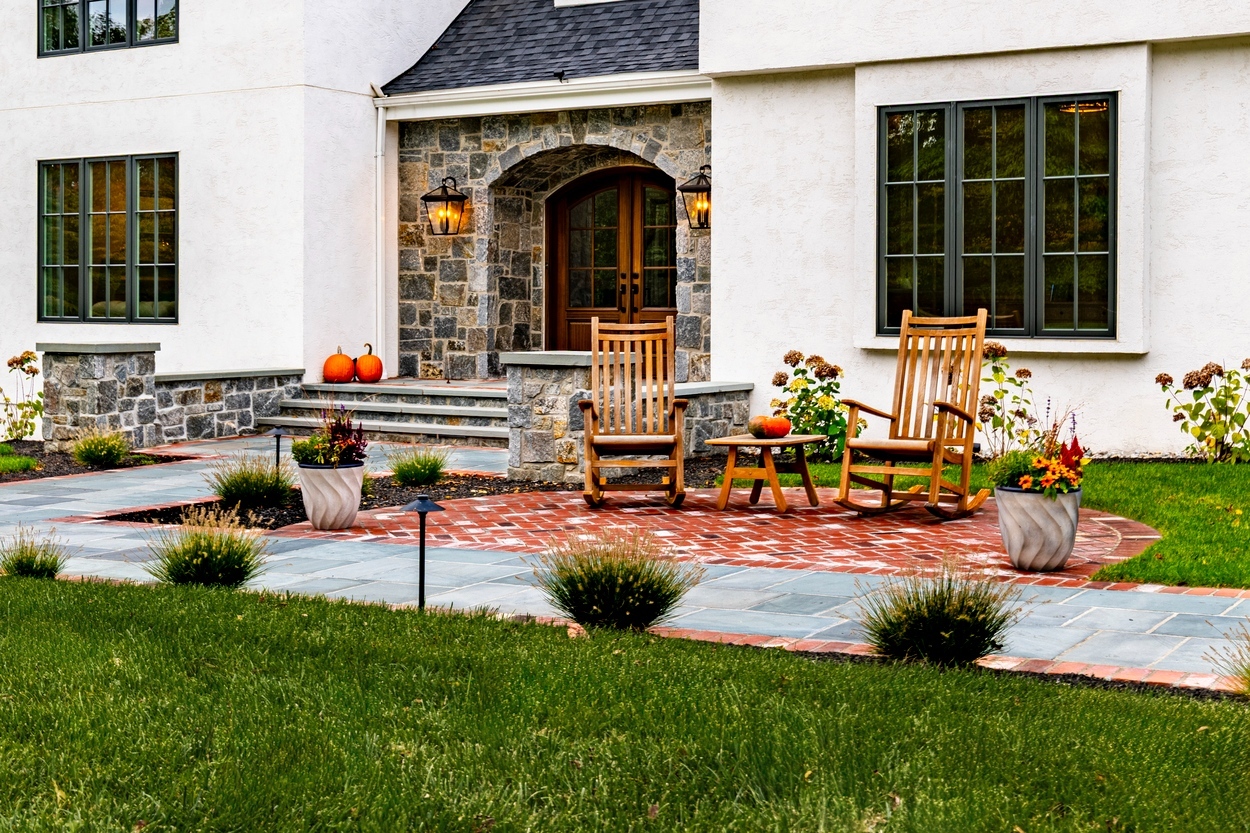 Rocking chair patio with seasonal décor on a brick circle, part of custom hardscaping, landscaping and lighting in Wilmington, DE
