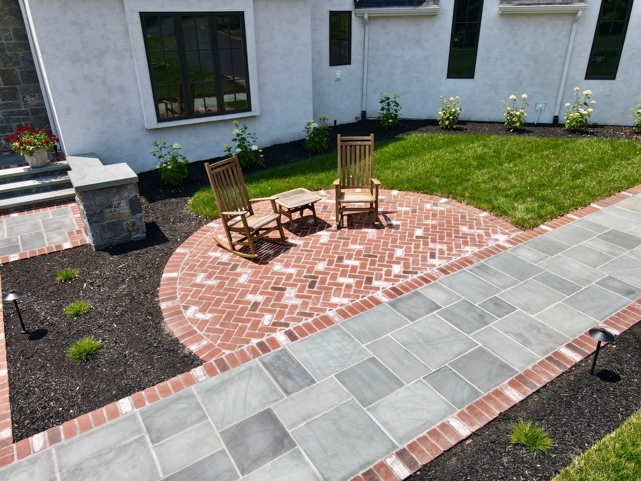Brick paver circular patio with rocking chairs in a custom hardscaping and landscaping project in Wilmington, DE