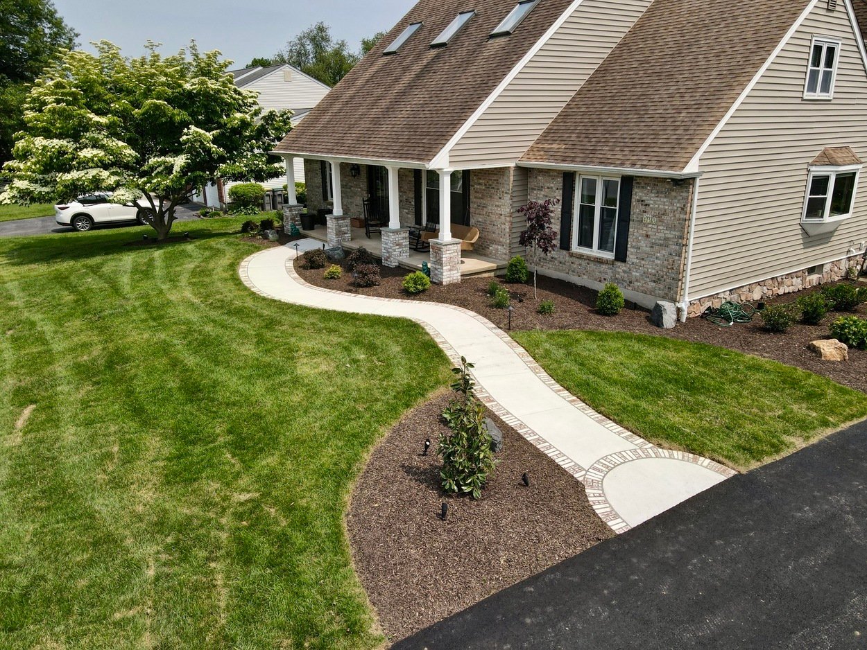 Curved front walkway with brick border and manicured lawn for custom hardscaping and landscaping in Wilmington, DE