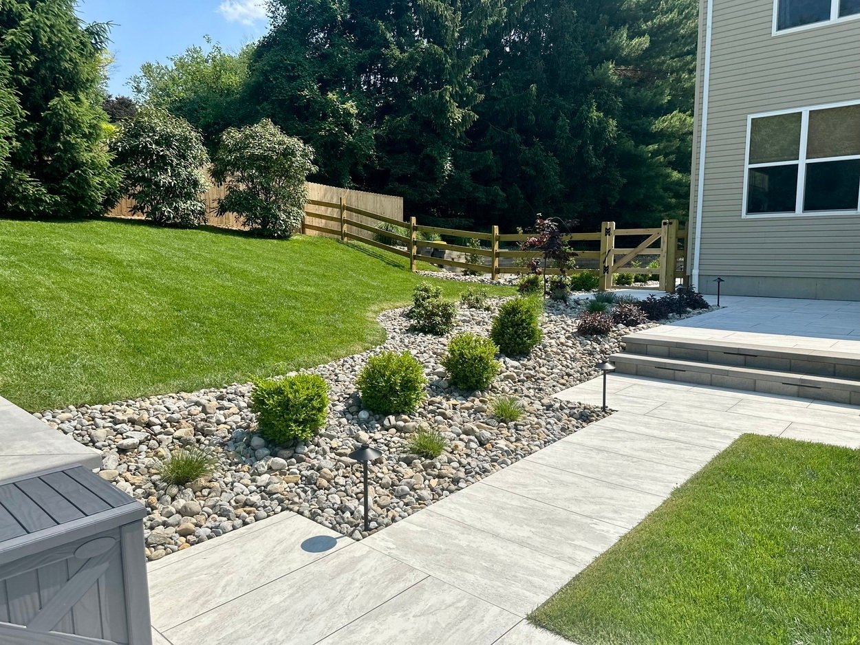 Custom landscaping featured along porcelain patio walkway in Newark, DE