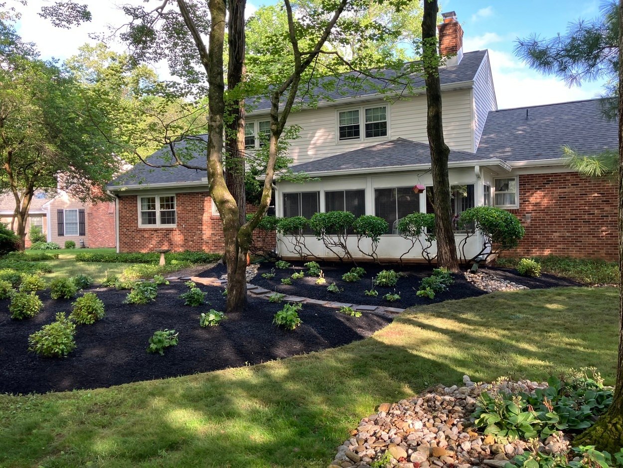 Landscaped house with green lawn, plants and mulched beds by First Class Lawncare, LLC in Wilmington, DE