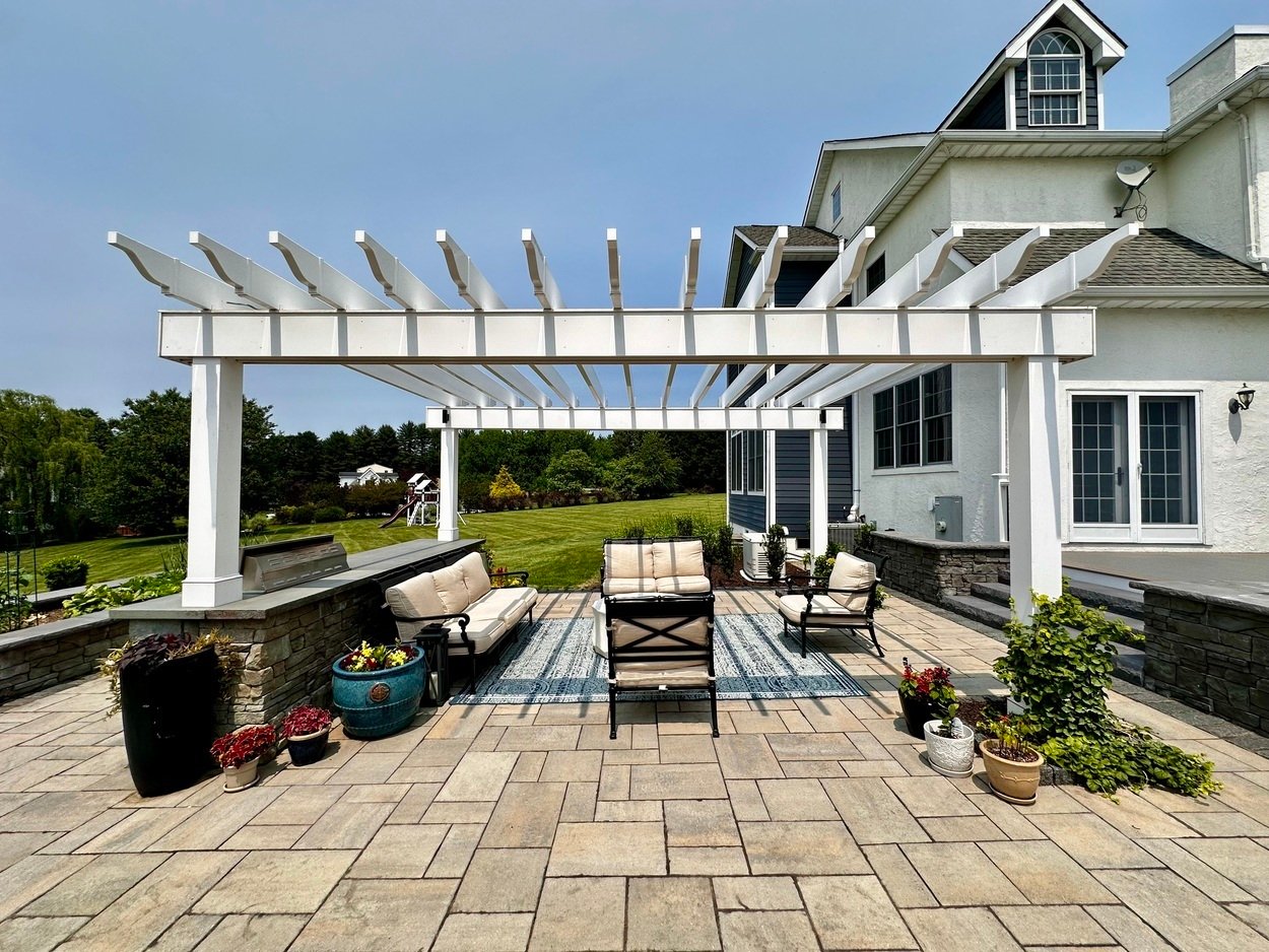 Backyard patio with white pergola and cushioned seating for an outdoor living project in Newark, DE