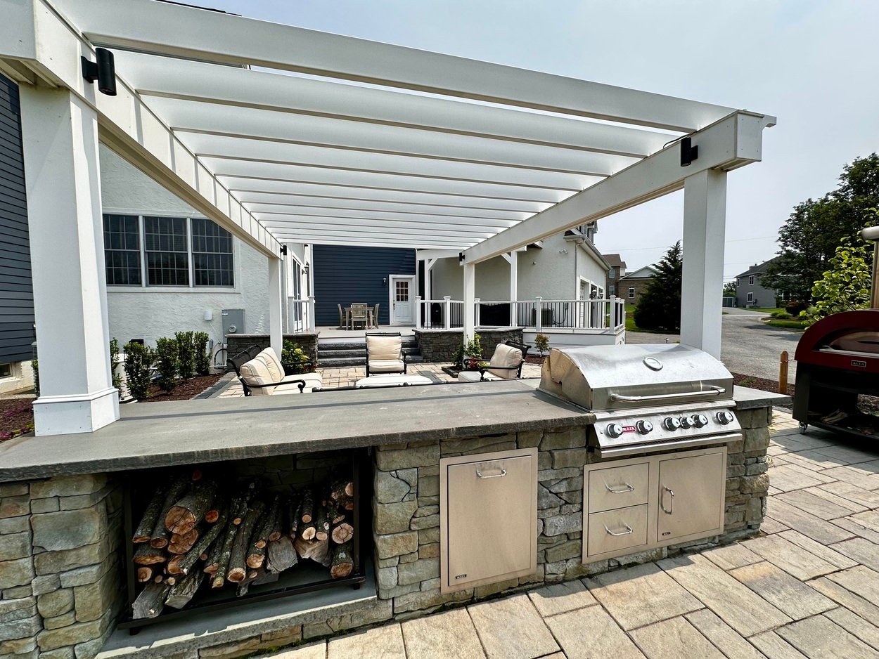 Built-in grill station and wood storage with pergola and seating area in an outdoor living project in Newark, DE
