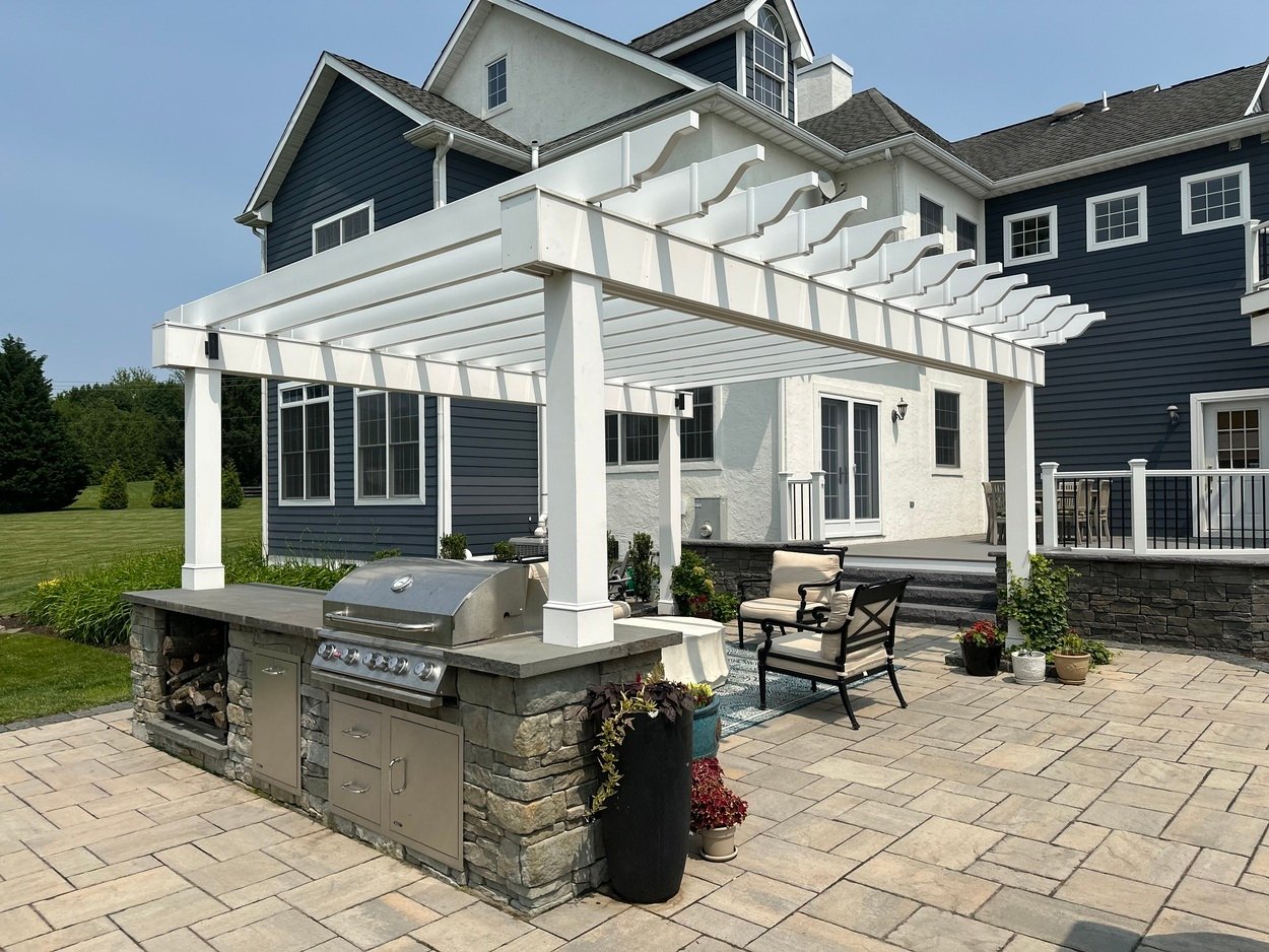Outdoor kitchen with built-in grill and wood storage under pergola in Newark, DE