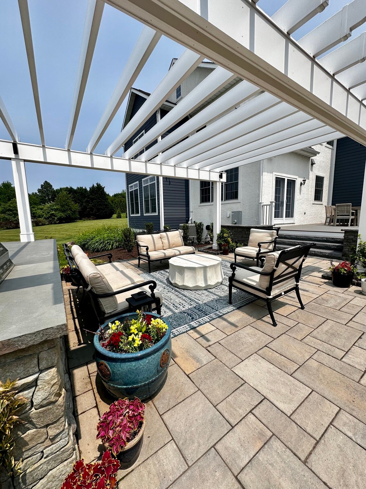 Outdoor lounge area with cushioned seating beneath a pergola in an outdoor living project in Newark, DE
