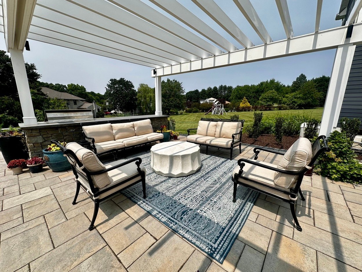 Outdoor rug and cushioned seating under a white pergola in an outdoor living project in Newark, DE