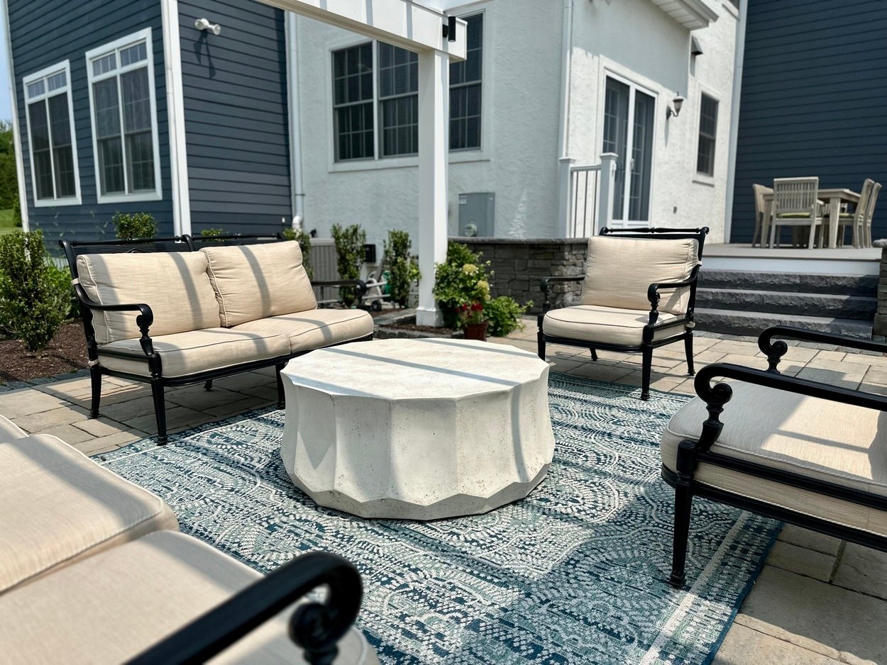 Patio furniture around a modern white table under pergola in Newark, DE outdoor living project