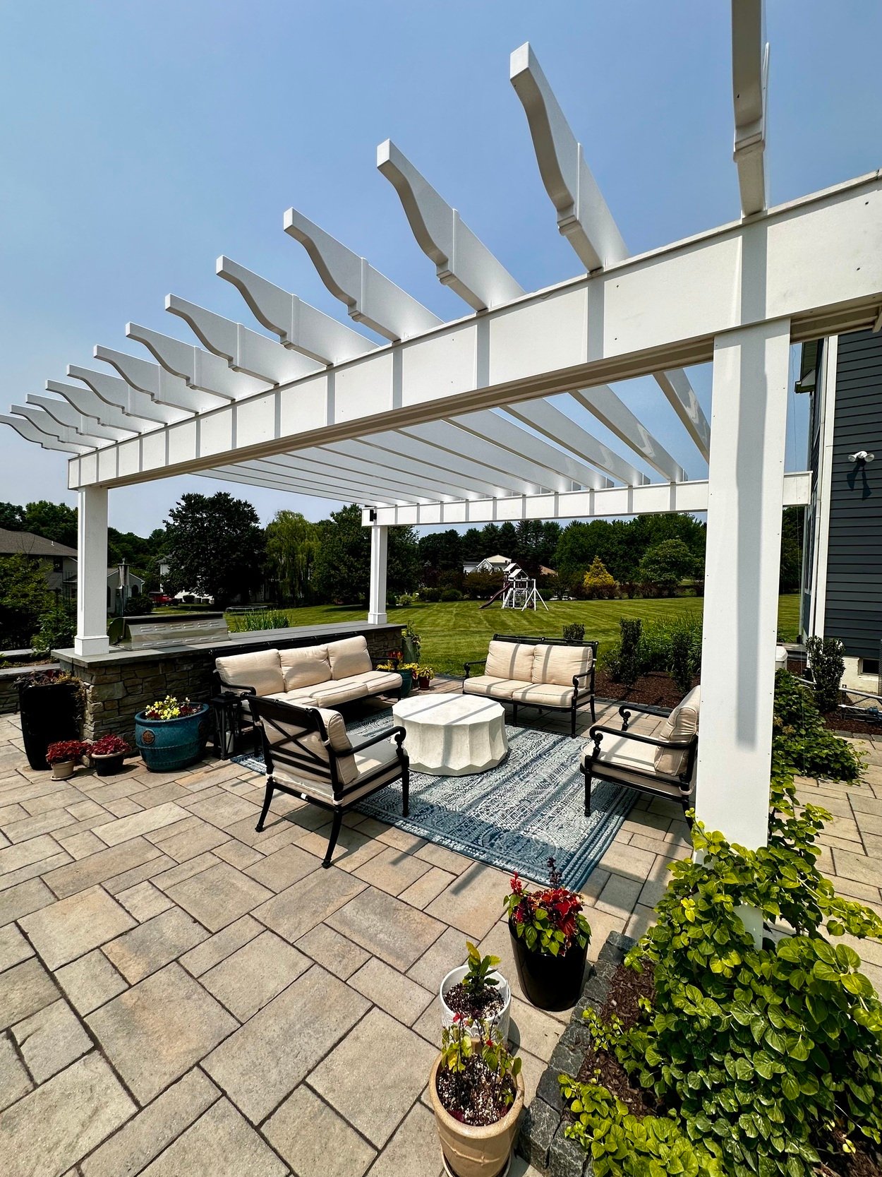 Patio lounge with pergola, decorative planters, and lush lawn in outdoor living project in Newark, DE