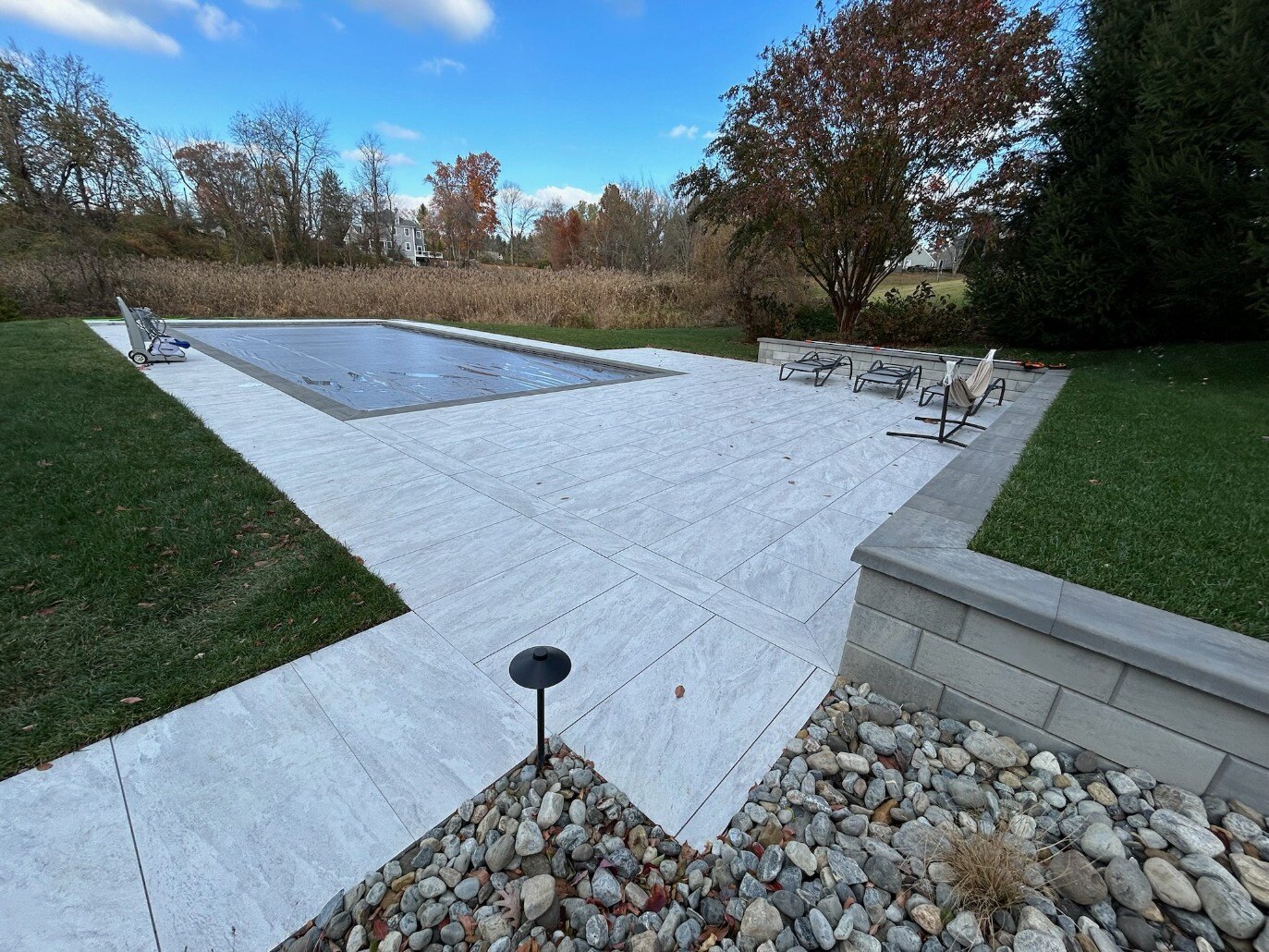 A custom backyard with a sleek porcelain patio and stylish lounge chairs in Newark, DE by First Class Lawn Care.