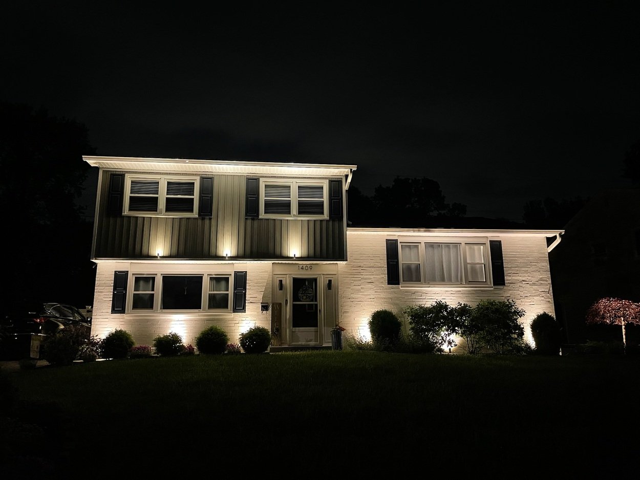 Two-story house illuminated with outdoor lighting by First Class Lawncare, LLC in Wilmington, DE