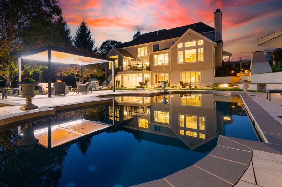 Evening view of a modern hardscape with poolside lighting and pergola, in West Chester, PA by First Class Lawn Care