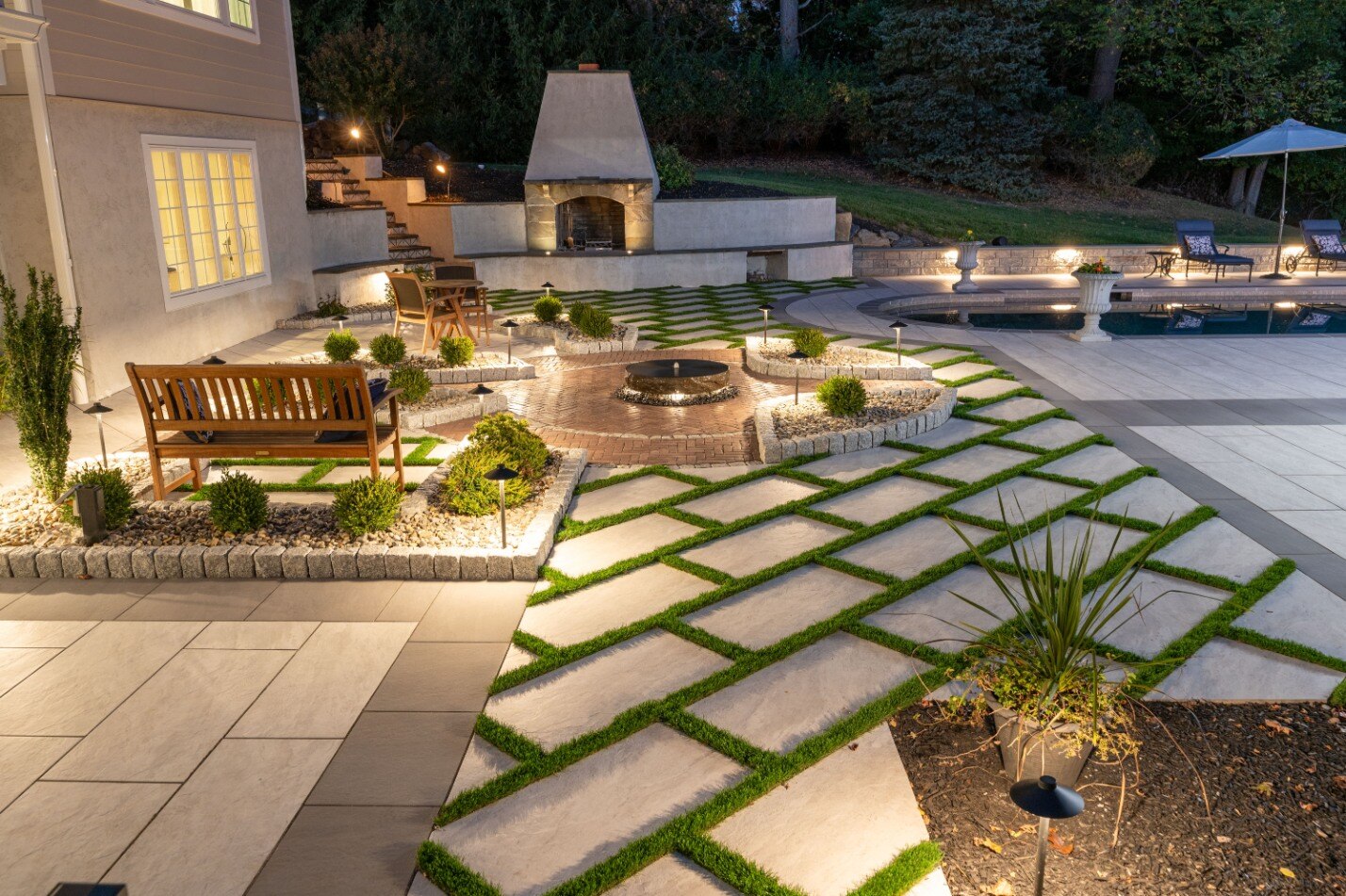 West Chester English garden inspired backyard hardscaping lit by landscape lighting by First Class Lawn Care in Wilmington, DE