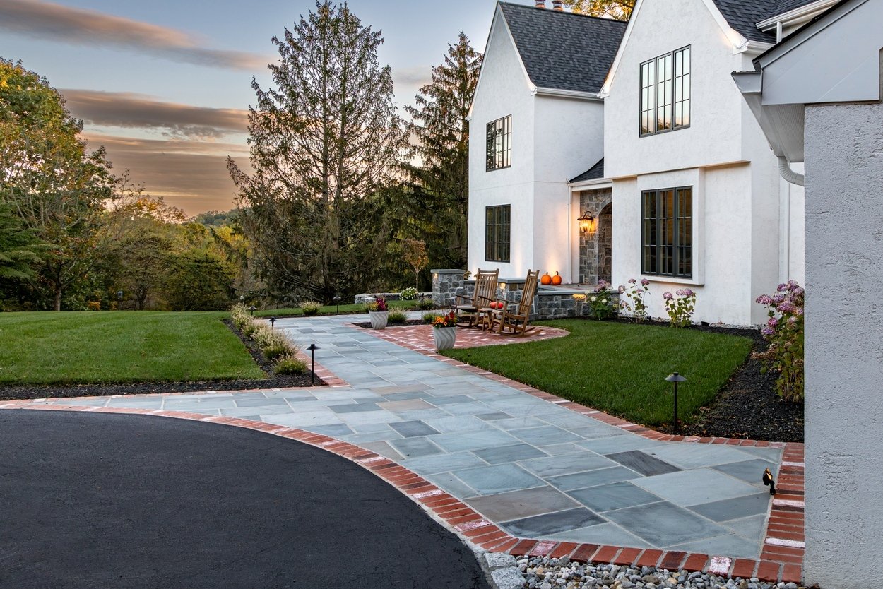Curved front walkway with brick border and accent lighting showcasing custom hardscaping, landscaping and lighting in Wilmington, DE