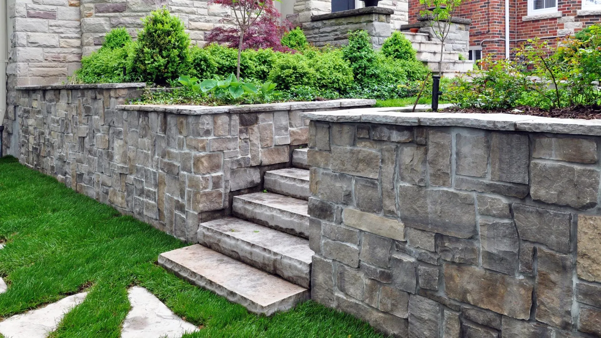 Stone retaining wall with stairs and landscaped flower beds